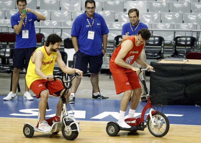 Sergio Llull (L) and Rudy Fernandez play with electric tricycles after a training session of the Spanish basketball team ahead o