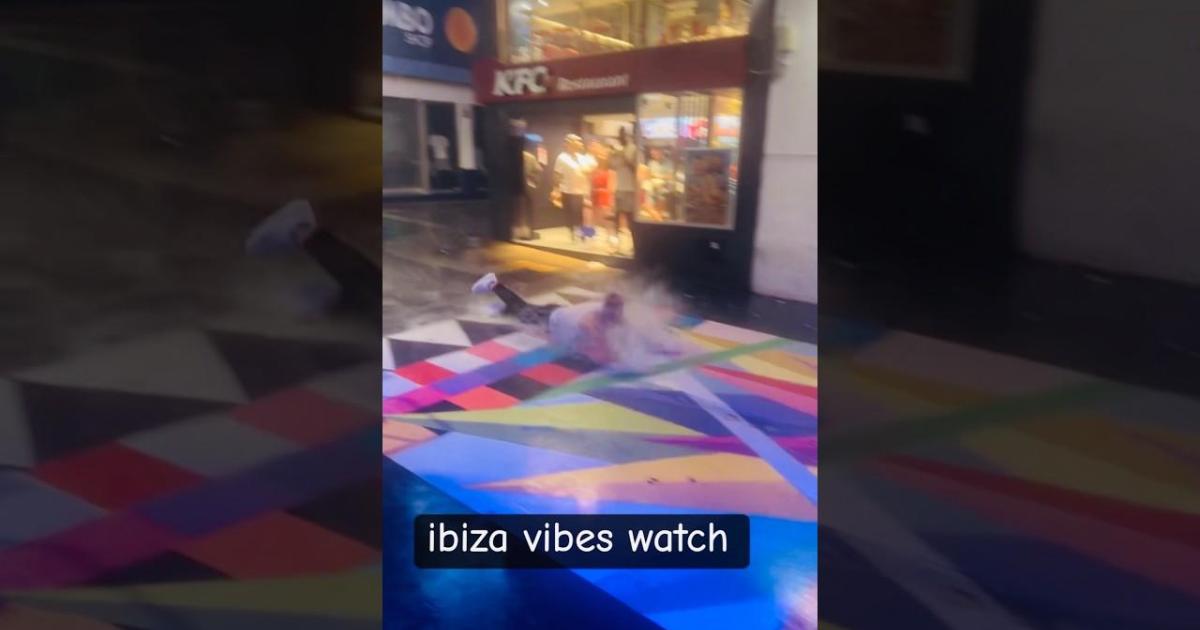Un turista aprovecha las lluvias torrenciales para deslizarse cuesta abajo sobre la obra de Okuda en Sant Antoni